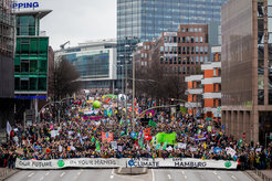 Dichtgedrängter Demonstrationszug, der eine sechsspurige Straße einnimmt. In der ersten Reihe tragen die Demonstrantinnen und Demonstranten ein Banner über die ganze Breite des Zuges mit verschiedenen Aufschriften: Our future in our hands, Save the climate und Save Hamburg